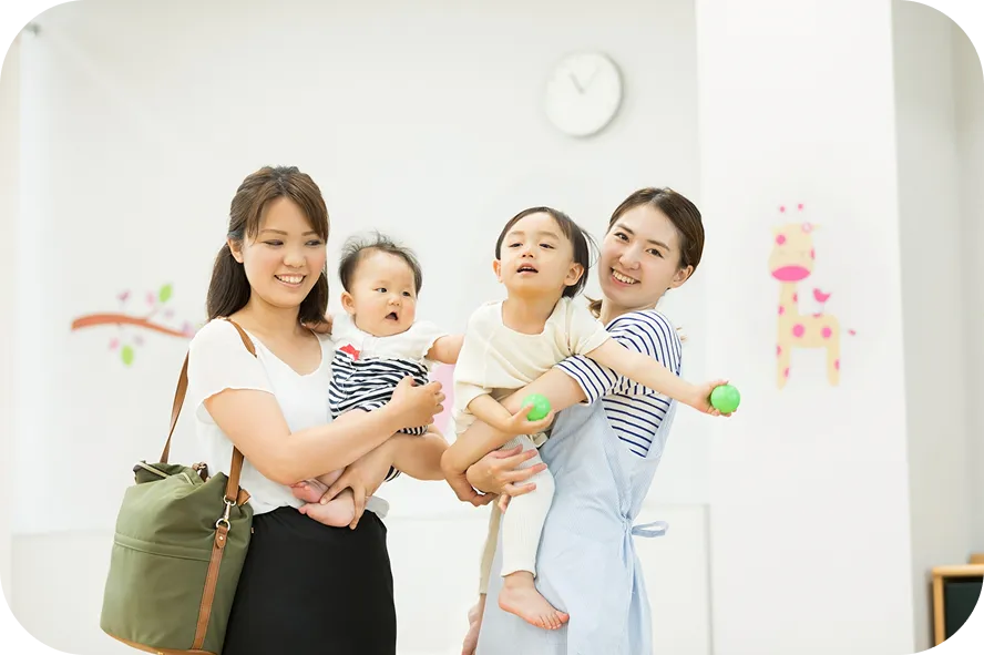 子どもを抱く保護者と保育士
